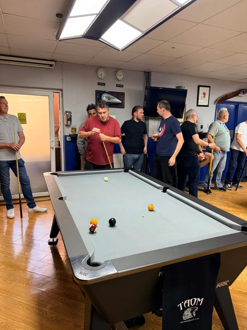 A pool table with grey cloth, red and yellow balls and players at Spots & Stripes